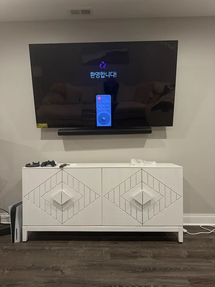 TV with a soundbar mounted beneath it above a white cabinet