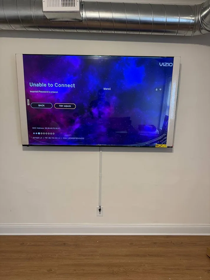 Wall-mounted TV with a white cord cover running down to the outlet