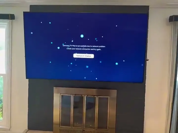 Large TV mounted on a dark painted fireplace wall above the firebox doors