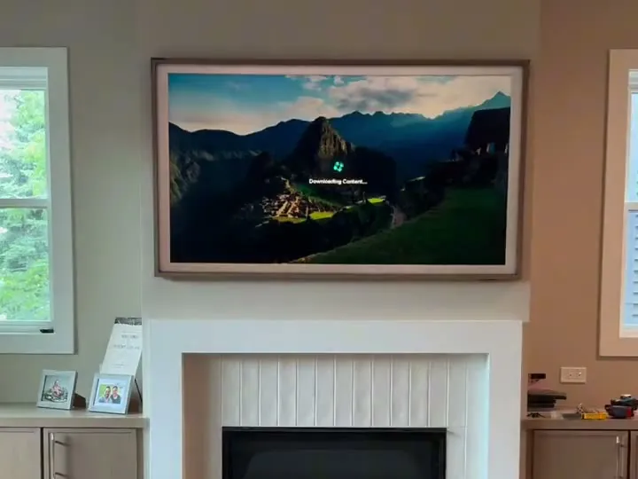 Samsung Frame TV with a wood-tone bezel mounted above a white fireplace