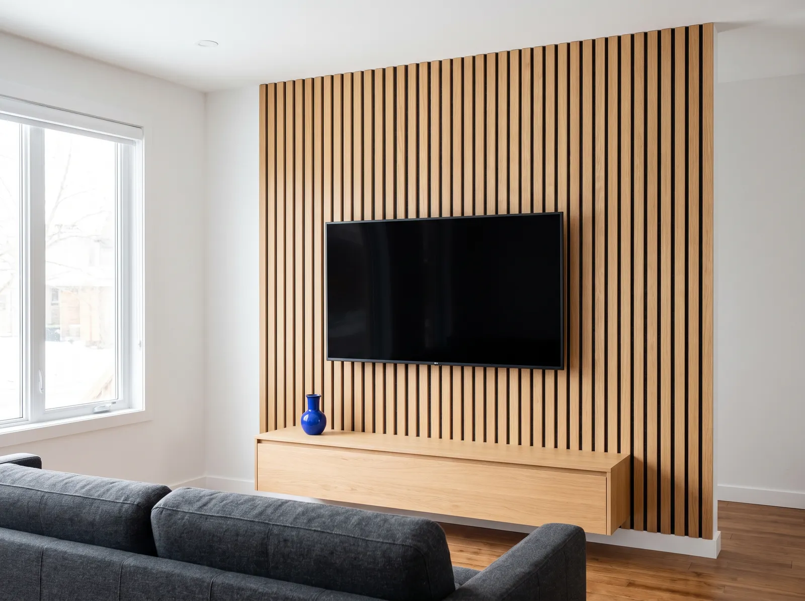 TV centered on a light-oak slat feature wall above a floating console