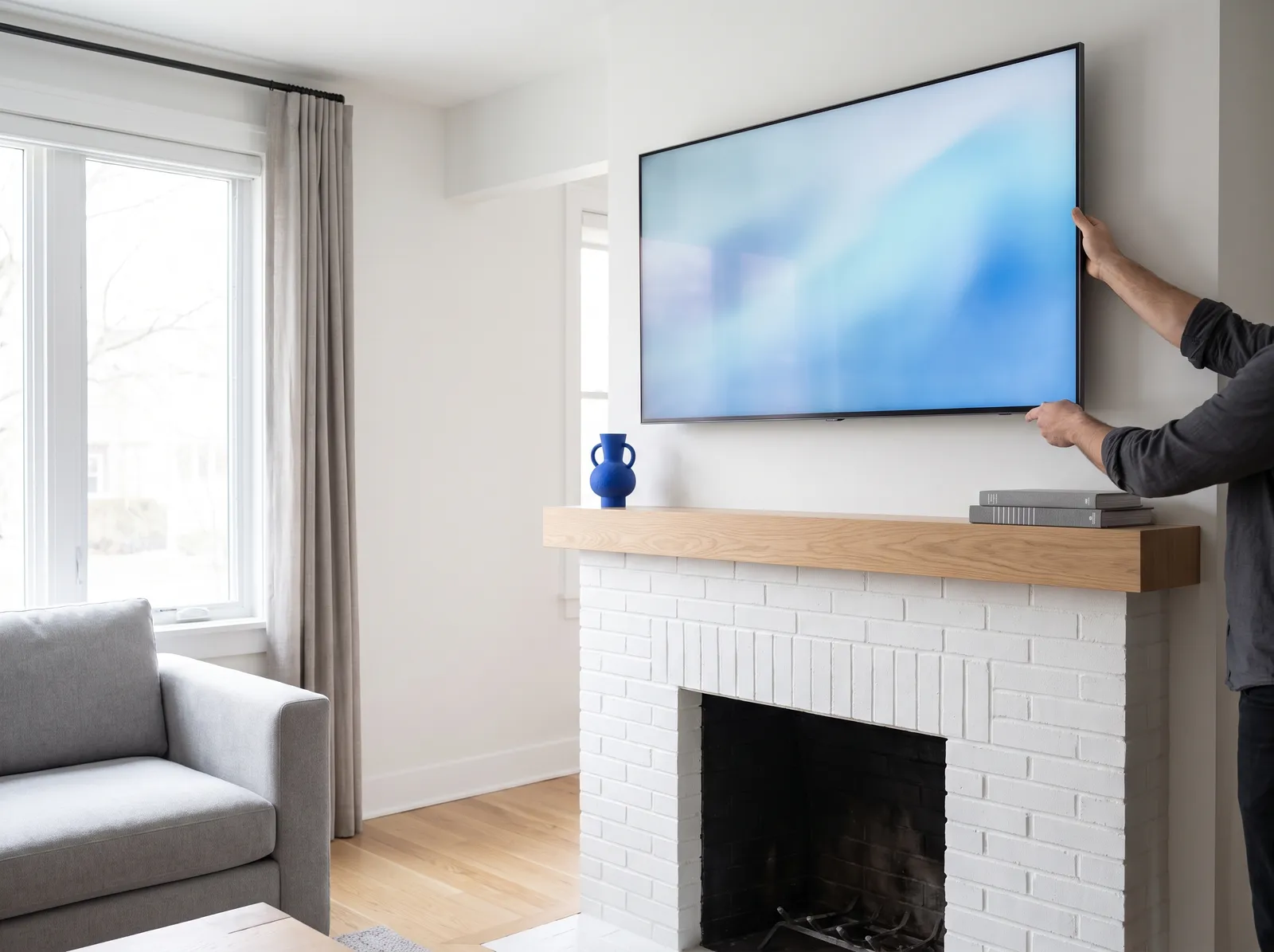 Installer mounting a TV above a painted brick fireplace with no cables on the brick