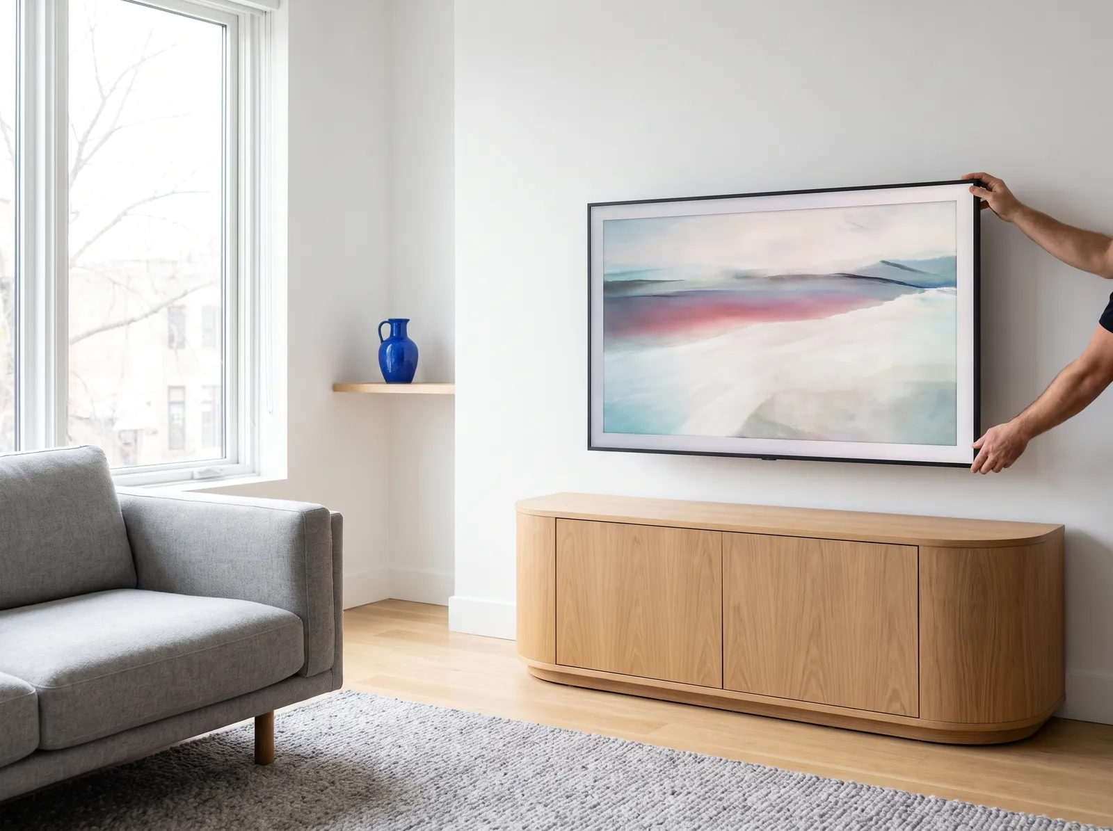 Installer centering an art TV over a curved oak console