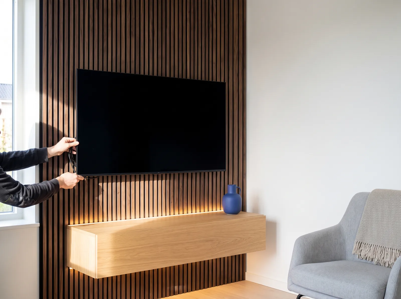 Walnut slat accent wall behind a TV with LED underglow